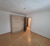 A room in a 2-room apartment with a wooden decor floor and a built-in wardrobe.