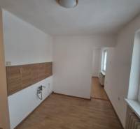 A kitchenette in a 2-room apartment with a wooden decor floor and a window.