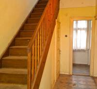 The interior of a family house with a wooden staircase and tiled floor.