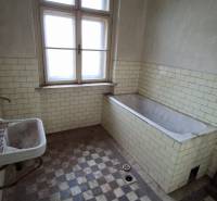 A bathroom in a family house with a bathtub and a tiled wall.