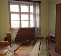 A room in a family house with old furniture and a window with transparent curtains.
