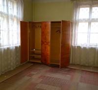 A room in a family house contains an older wardrobe and carpets with a delicate pattern.