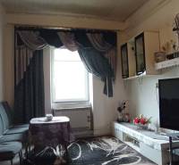 Living room in a two-room apartment with a television, sofa, and decorative curtains.