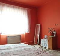 A bedroom in a two-room apartment with bright orange walls and a carpet.