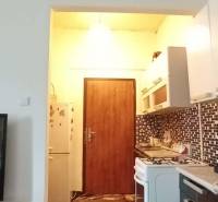A kitchen with a counter and a stove in a 2-room apartment, mosaic tiles on the wall.