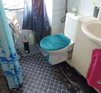 Bathroom in a 2-room apartment with white tiles and patterned floor.
