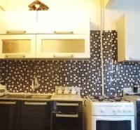A kitchen in a 2-room apartment with mosaic tiles and a kitchen unit.