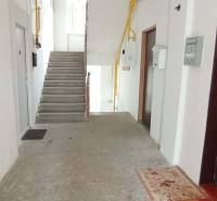 A corridor with concrete stairs and entrances to 2-bedroom apartments on Partizánska Street in Lučenec.