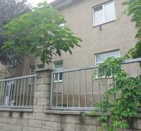 The exterior of the house with a stone fence and greenery on Partizánska Street in Lučenec.