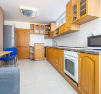 A kitchen with wooden cabinets and appliances, a family house, white tiles.