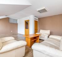 Living room with white armchairs, a wooden table, and a wooden-patterned floor in a family house.