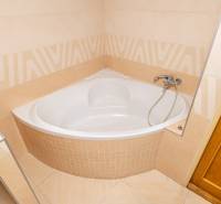 Bathroom with a corner bathtub and tiling in a family house.