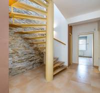 Interior of a family house with a spiral staircase and tiling, stone cladding on the wall.