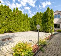 A family house on Bencúrova Street in Bratislava-Ružinov with a paved garden and thuja trees.