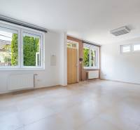 A spacious room with large windows, a wooden decor floor, entrance doors.