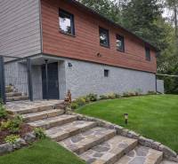 The exterior of the cottage near Zvolen with stone steps, wooden cladding, and a well-maintained lawn.