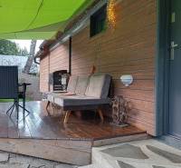 A cottage in Zvolen with an outdoor wooden terrace, a seating set, and stone paving.