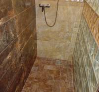 A shower corner in a cabin with stoneware tiles and glass bricks in a minimalist design.