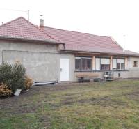 A family house in Kolárovo with a red roof and an unkempt garden.