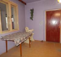 Purple room in a family house with doors, a table, and a wooden-patterned floor.
