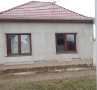 A family house in Kolárovo has a gray facade, a sloped red roof, and two windows.