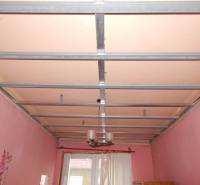 A room in a family house with a metal ceiling structure and pink walls.