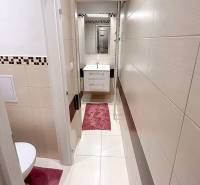 A bathroom with white tiles and red accessories in a two-room apartment.