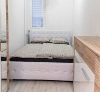 Bright bedroom with a bed, wooden decor, and a dresser in a studio apartment.