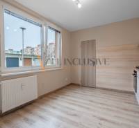 A kitchen in a one-room apartment with a wooden decor floor.