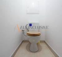 A simple toilet with light tiles in a studio apartment.