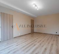 An empty room in a one-bedroom apartment, wooden decor flooring, light chandelier.