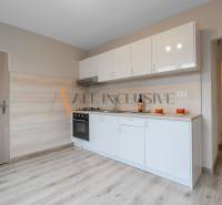 A kitchen with white cabinets in a studio apartment, floor with wood decor.
