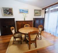 Dining room in a family house with wooden furniture, floor with wooden decor, paintings on the walls.