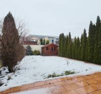 A garden with a wooden gazebo and trees by a family house on Púchovská Street in Košice.