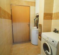 Laundry room in a family house with a washing machine and a boiler, tiled with light tiles.