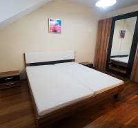 A bedroom in a family house with a bed and a wardrobe, floor with a wooden decor.