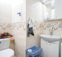 Bathroom in a 2-room apartment with decorative tiles and a sink with a cabinet.