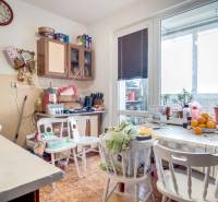A kitchen in a 2-room apartment with a dining table, flowers, and a floor with a wooden decor.