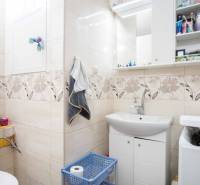 Bathroom in a 2-room apartment with patterned tiles, a sink, and storage space.