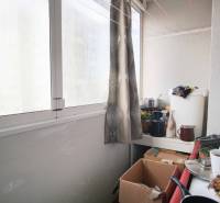 A glazed loggia in a 2-room apartment with lots of boxes and curtains for privacy.