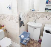 Bathroom in a 2-room apartment with a washing machine, cabinet, and decorative tiles.