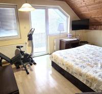 A bedroom in a family house with a bed, an exercise bike, and a wooden decor floor.