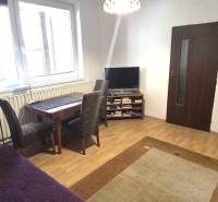 Living room in a family house with wood-patterned flooring, a television, and a dining table.