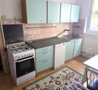 A kitchen with a gas stove, green cabinets, and a table in a family house.