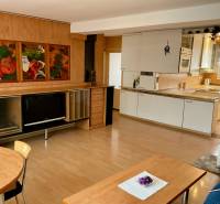 Living room with kitchen in a three-room apartment, wooden decor flooring, painting on the wall.