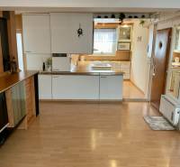 A kitchen in a 3-room apartment with a wood-patterned floor and built-in appliances.
