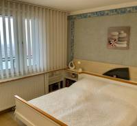 Bedroom in a 3-room apartment with a bed, vertical blinds, and a picture on the wall.