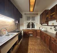 A kitchen in a 3-room apartment with a wood-patterned floor and dark furniture.