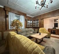 Living room in a 3-room apartment with a wooden decor floor, wooden paneling, and chandeliers.