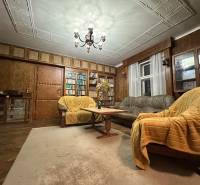 A living room with a wood-patterned floor, wooden paneling, and lots of books.